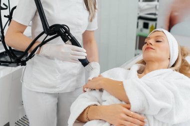 Genç bir kız güzellik salonunda ellerinin derisi için karbon soyuluyor. Lazer darbeleri deriyi temizler. Donanım kozmetolojisi. Fototermoliz süreci, deriyi ısıtır..