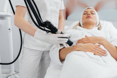 Genç bir kız güzellik salonunda ellerinin derisi için karbon soyuluyor. Lazer darbeleri deriyi temizler. Donanım kozmetolojisi. Fototermoliz süreci, deriyi ısıtır..