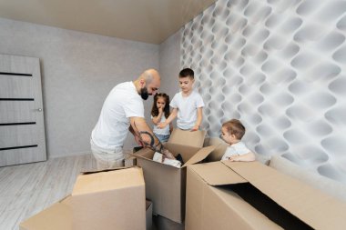 Çocuklu genç bir baba, yeni bir daireye taşındıktan sonra bir kutu eşyayı boşaltıyor. Gayrimenkul alımı. Ev ısınması, mal teslimatı ve taşımacılığı.