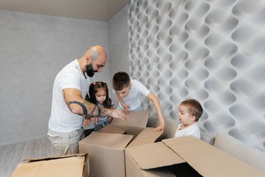 Çocuklu genç bir baba, yeni bir daireye taşındıktan sonra bir kutu eşyayı boşaltıyor. Gayrimenkul alımı. Ev ısınması, mal teslimatı ve taşımacılığı.