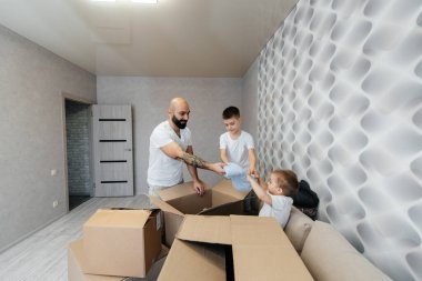 Çocuklu genç bir baba, yeni bir daireye taşındıktan sonra bir kutu eşyayı boşaltıyor. Gayrimenkul alımı. Ev ısınması, mal teslimatı ve taşımacılığı.