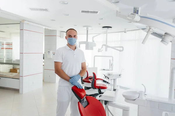 Ein Junger Zahnarzt Mit Maske Steht Neben Einem Roten Zahnarztstuhl — Stockfoto