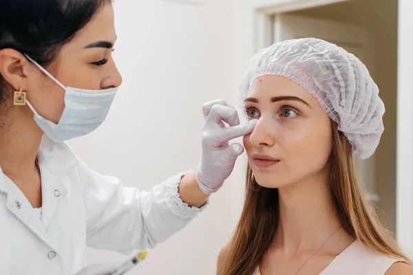 美容師は若い美少女のために眼の周りの鼻の毛細管とメソセラピーを埋める手順の後 患者の顔を拭く 近代化粧品 — ストック写真