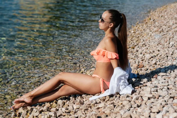 一个戴着眼镜和比基尼的年轻貌美的女人正坐在海面上 在阳光灿烂的日子里享受着假期 旅游业和旅游旅行 开放边界和休假 — 图库照片