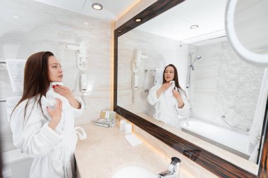Genç ve güzel bir kız güzel beyaz bir banyoda yıkanır. Otelde taze bir günaydın. Dinlen ve seyahat et. Otel eğlencesi ve turizm..