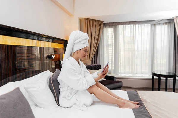 Beyaz önlüklü güzel bir kız otel odasında telefonla konuşuyor. Dinlen ve seyahat et. Otel eğlencesi ve turizm..