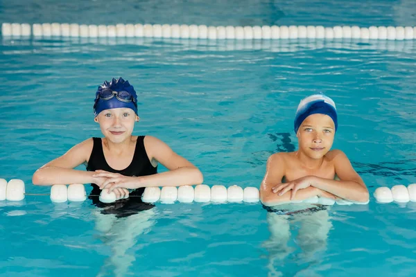 A boy and a girl play together and learn to swim in a modern swimming pool. Development of children's sports. Healthy upbringing of children and popularization of children's sports.