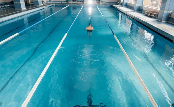 若い男が近代的なスイミングプールでトレーニングや水泳をします スポーツ開発 競技の準備 健康的なライフスタイル 水処理と健康的なライフスタイル — ストック写真