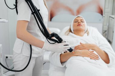 Genç bir kız güzellik salonunda ellerinin derisi için karbon soyuluyor. Lazer darbeleri deriyi temizler. Donanım kozmetolojisi. Fototermoliz süreci, deriyi ısıtır..