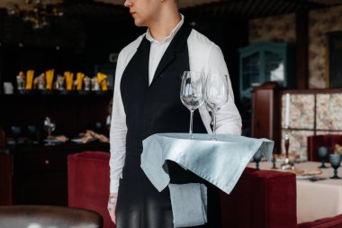 Şık üniformalı genç bir erkek garson güzel bir gurme restoranında masaya servis yapmakla meşgul. Üst düzey bir restoran. Restorandaki masa servisi..