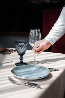 Şık üniformalı genç bir garson güzel bir gurme restoranında masaya servis yapmakla meşgul. Restorandaki masa servisi..