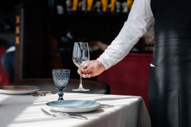 Şık üniformalı genç bir garson güzel bir gurme restoranında masaya servis yapmakla meşgul. Restorandaki masa servisi..