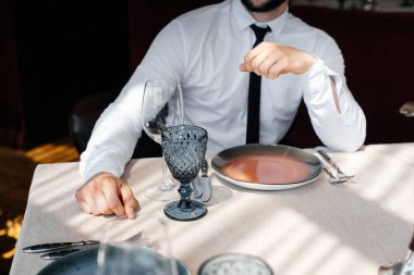 Genç sakallı bir erkek işadamı iyi bir restoranda bir masada oturuyor ve emirlerini bekliyor. Yemek şirketinde müşteri hizmetleri..