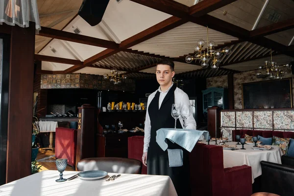 一位穿着时髦制服的年轻男服务员在一家漂亮的美食家餐厅里为餐桌服务 一个高级餐厅 餐厅的餐桌服务 — 图库照片