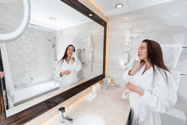 Genç ve güzel bir kız güzel beyaz bir banyoda yıkanır. Otelde taze bir günaydın. Dinlen ve seyahat et. Otel eğlencesi ve turizm..