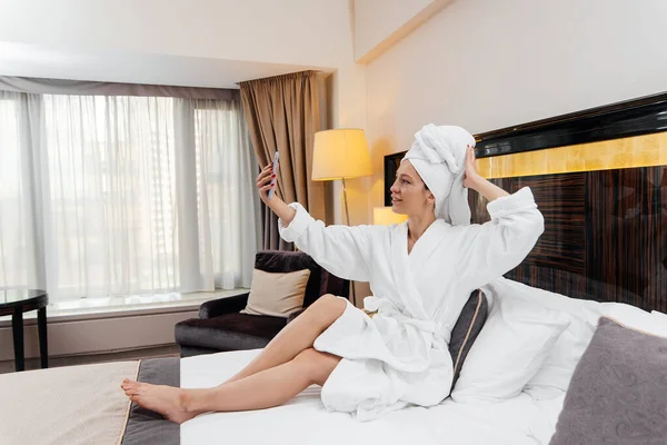 Beyaz önlüklü güzel bir kız otel odasında telefonla konuşuyor. Dinlen ve seyahat et. Otel eğlencesi ve turizm..