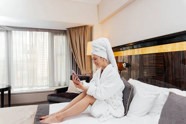 Beyaz önlüklü güzel bir kız otel odasında telefonla konuşuyor. Dinlen ve seyahat et. Otel eğlencesi ve turizm..