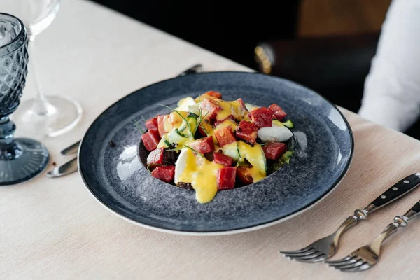 Garson, taze sebze salatası ve ton balığının üzerine sos döker. Sağlıklı yiyecekler. Yakından haute mutfağının nefis lezzetleri..