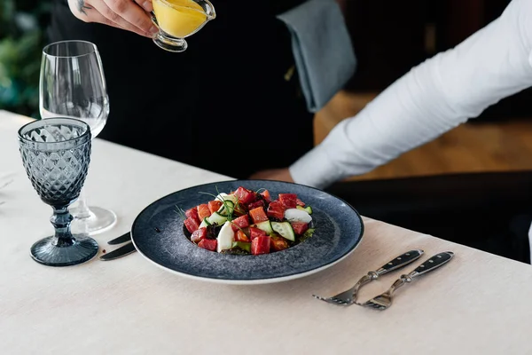 Garson, taze sebze salatası ve ton balığının üzerine sos döker. Sağlıklı yiyecekler. Yakından haute mutfağının nefis lezzetleri..
