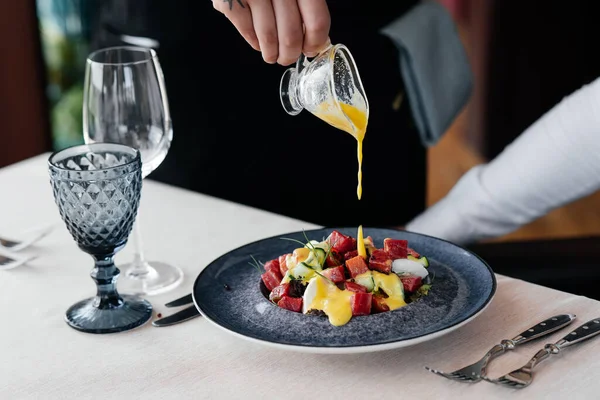 Garson, taze sebze salatası ve ton balığının üzerine sos döker. Sağlıklı yiyecekler. Yakından haute mutfağının nefis lezzetleri..