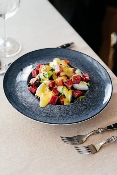 Garson, taze sebze salatası ve ton balığının üzerine sos döker. Sağlıklı yiyecekler. Yakından haute mutfağının nefis lezzetleri..