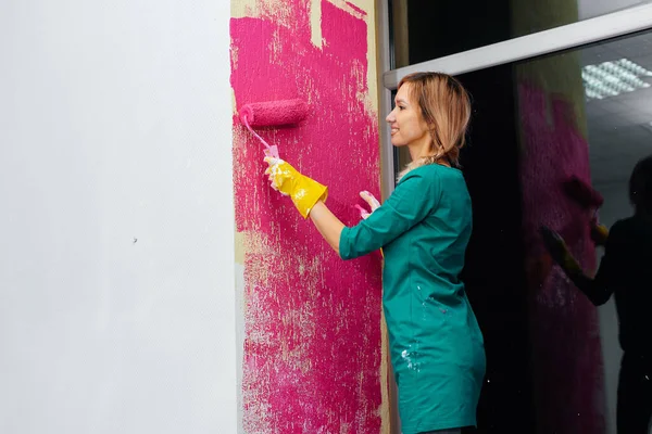 Une Jeune Fille Peint Mur Avec Rouleau Rose Dans Son Image En Vente