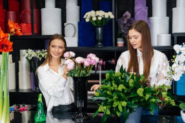 İki genç kadın telefonla sipariş alır ve rahat bir çiçekçide güzel şenlik buketleri yaparlar. Çiçekçi dükkanında çiçek buketi yapıyorlar. Küçük işletme.