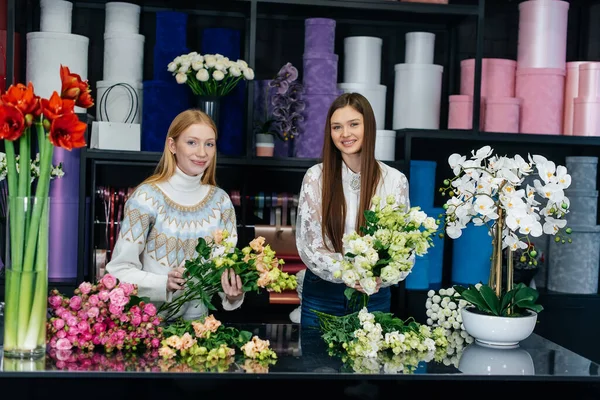 两个年轻的女人通过电话下订单 在一家舒适的花店里做美丽的节日花束 花店里的花卉和花束制作 小商业 — 图库照片