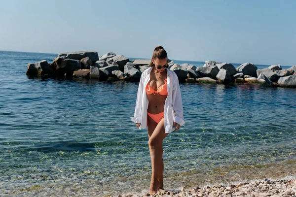 Egy Gyönyörű Fiatal Bikiniben Sétál Óceán Partján Hatalmas Sziklák Hátterében — Stock Fotó