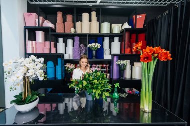 Genç bir çiçekçi kadın, güzel bir çiçek buketi yapımı için telefonla siparişi kabul ediyor. Çiçekçilik ve çiçekçide kova yapmak. Küçük işletme.