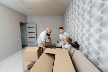 Çocuklu genç bir baba, yeni bir daireye taşındıktan sonra bir kutu eşyayı boşaltıyor. Gayrimenkul alımı. Ev ısınması, mal teslimatı ve taşımacılığı.