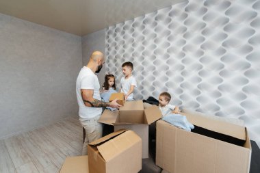 Çocuklu genç bir baba, yeni bir daireye taşındıktan sonra bir kutu eşyayı boşaltıyor. Gayrimenkul alımı. Ev ısınması, mal teslimatı ve taşımacılığı.