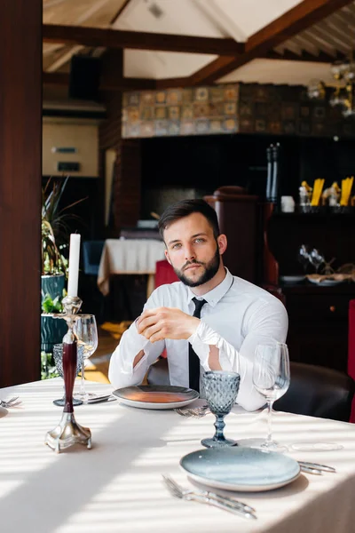 Genç sakallı bir erkek işadamı iyi bir restoranda bir masada oturuyor ve emirlerini bekliyor. Yemek şirketinde müşteri hizmetleri..