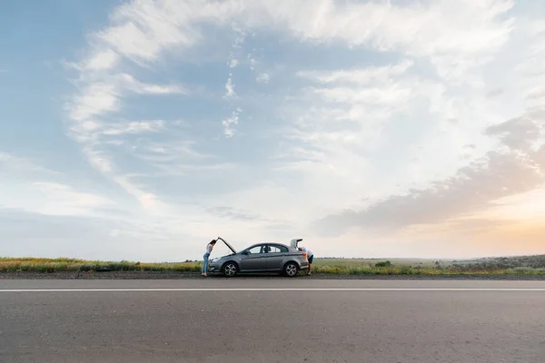 Una Joven Para Cerca Coche Averiado Medio Carretera Durante Atardecer — Foto de Stock