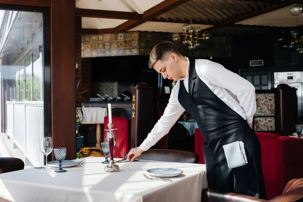 Jeune Garçon Dans Uniforme Élégant Est Engagé Dans Service Table Photos De Stock Libres De Droits