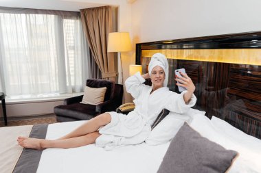 Beyaz önlüklü güzel bir kız otel odasında telefonla konuşuyor. Dinlen ve seyahat et. Otel eğlencesi ve turizm..