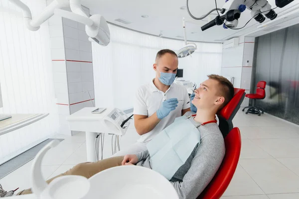 Młody Dentysta Bada Leczy Zęby Młodego Mężczyzny Nowoczesnym Białym Gabinecie — Zdjęcie stockowe