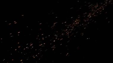 Gece gökyüzündeki büyük ateşten yanan kırmızı kıvılcımlar yükseliyor. Ateş, ışık ve yaşam temasının güzel soyut arkaplanı.