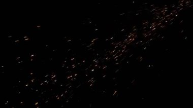 Gece gökyüzündeki büyük ateşten yanan kırmızı kıvılcımlar yükseliyor. Ateş, ışık ve yaşam temasının güzel soyut arkaplanı.