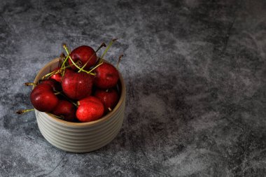 Bowl of tasty cherries on grey counter top.