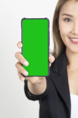 Siyah takım elbiseli bir iş kadını beyaz arka planda yeşil ekranda akıllı telefon görüntüsü gösteriyor. İş kadınının yarısı elinde yeşil ekranlı akıllı telefon tutuyor.. 