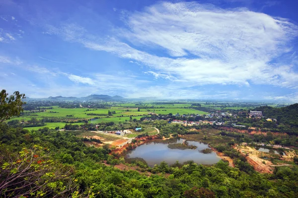 Açık mavi gökyüzü ve beyaz bulutlar altında Tayland kırsalındaki verimli tarım topluluğunun yüksek açılı fotoğrafı.