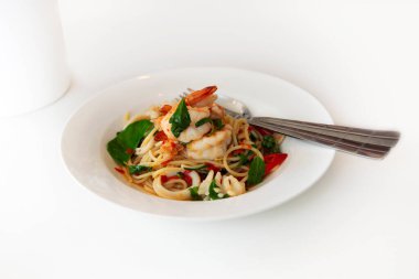 Seafood spaghetti flavored with little spicy oriental served on white plate.