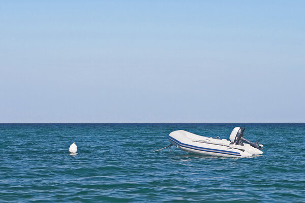 Anchored dinghy on sea with blue sky.