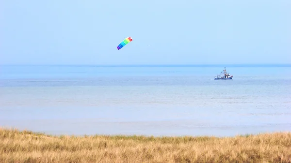 Nordsjökusten med crabber båt och wind kite på himlen Royaltyfria Stockbilder