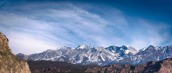 雪に覆われたアンデス山脈と アルゼンチンのメンドーサ州ポトレリロスから 晴れた明るい冬の日に見られる賢明な雲 ロイヤリティフリーのストック画像