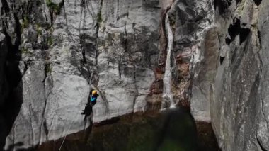 Tanımlanamayan bir kadın havadan şelaleden aşağı süzülürken zip ile iniyor. Ardeche boğazı, Güney Fransa
