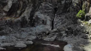 İnsanlar inebilir ve inebilir. Dağcılar kanyonda ipte sallanırken, arka planda kıvrımlı bir nehir vardı. Bir şelaleden aşağı süzülen havadan görüntü. Ardeche boğazı, Güney Fransa