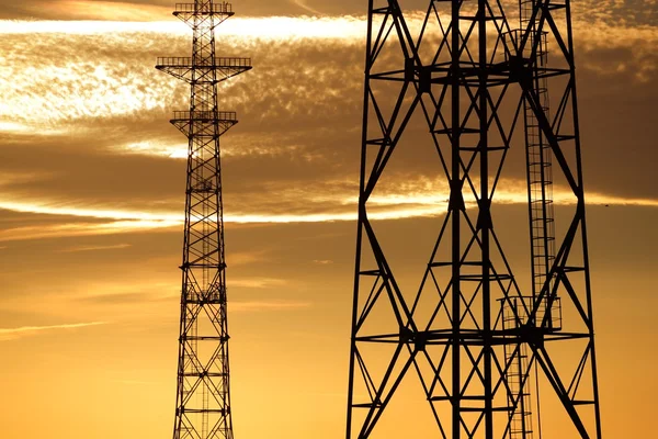 Eletricidade torres linha contra o pôr do sol céu — Fotografia de Stock