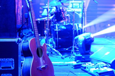 Konserden önce sahnede akustik gitar, davul seti, hoparlör ve diğer müzik ekipmanları. Neon ışığı. Görüntüyü algıla. Gece kulübü, performans, müzik grubu, şarkı söyleme, meslek, sanat, enstrüman